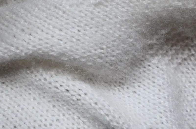 Maille blanche duveteuse en gros plan, dont les fibres fines forment un léger halo