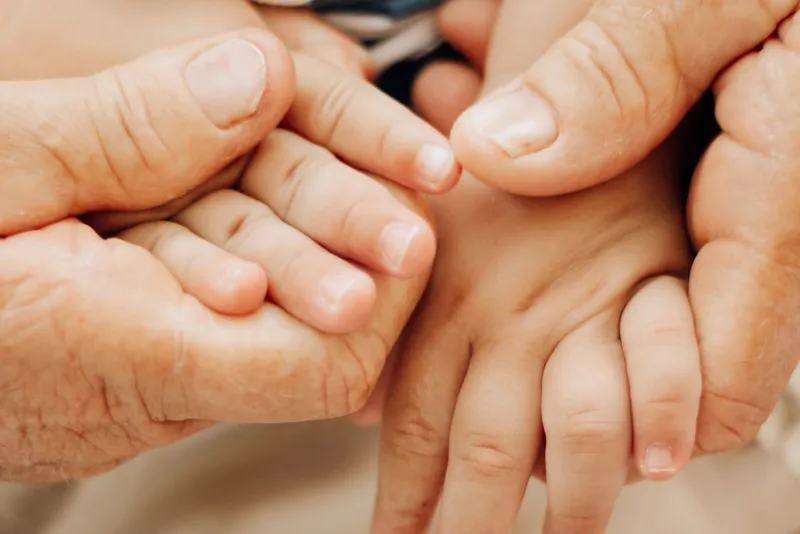 Mains ridées d'une personne âgée entourant les petites mains d'un enfant
